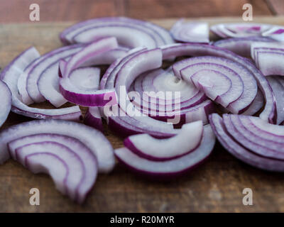 Preparazione alimentare, concetto di cucina a vista: fresche tagliate a fette le cipolle rosse sul rustico sfondo di legno Foto Stock