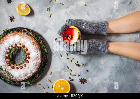 Mani femminili in muffole tenendo la tazza riempita con vin brulé. Vista superiore Foto Stock