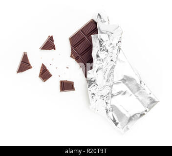 Barra di cioccolato Tablet avvolto in un foglio di alluminio isolato su sfondo bianco. Alcuni pezzi sono sparsi intorno. Ideale per i concetti. Foto Stock