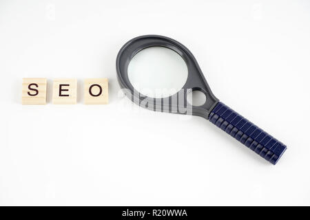 SEO, Ottimizzazione per i motori di ricerca parola raccolte di elementi in legno con le lettere e anche la lente di ingrandimento. Foto Stock