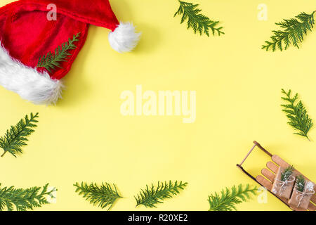 Natale con sfondo verde di Natale a rami di albero, decorazione di regali e scatole su sfondo giallo, vista dall'alto, copia spazio per il testo Foto Stock