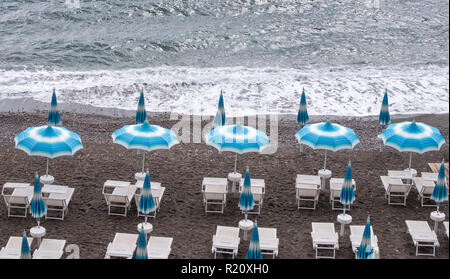 Righe del blu e del bianco di ombrelloni e lettini sulla spiaggia di Atrani sulla Costiera Amalfitana, Italia. Foto Stock