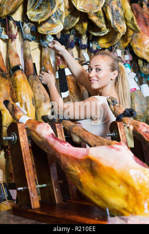 Allegro positivo femmina affascinante cliente che sceglie il prosciutto iberico nel negozio di carne Foto Stock