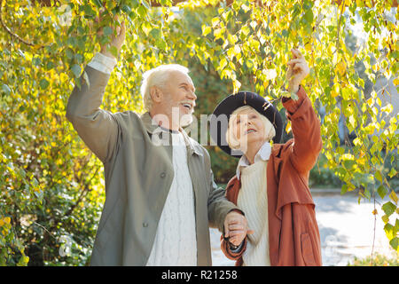 Positive le persone anziane in piedi sotto un albero Foto Stock