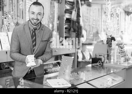 Sorridente venditore che mostrano differenti bracciali in gioielleria Foto Stock