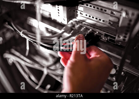 Close-Up del tecnico collegando il cavo patch in un rack server Foto Stock