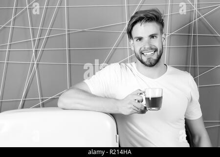 Uomo sorridente con la tazza di tè o caffè in cucina. Uomo sorridente con drink al retro frigo su sfondo rosa. Foto Stock