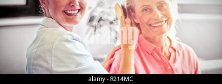 Infermiera femmina pettinare capelli di donna senior Foto Stock