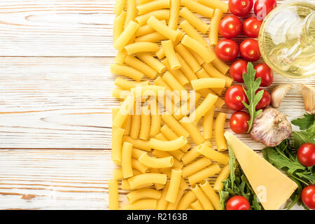 Ingredienti della cucina italiana per la cottura della pasta con per spazio copia di pomodori ciliegini rucola parmigiano rigatoni pasta aglio e olio di oliva. Concept food ricette top view flat lay Foto Stock