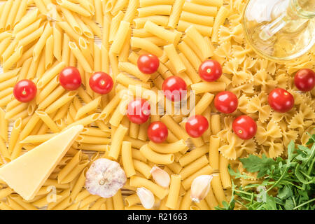 Ingredienti della cucina italiana per la cottura della pasta pomodorini rucola parmigiano rigatoni pasta aglio e olio di oliva. Concept food ricette top view flat lay Foto Stock
