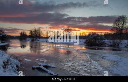 Un tramonto colorato su un fiume ghiacciato Wharfe vicino a Wetherby, West Yorkshire Foto Stock