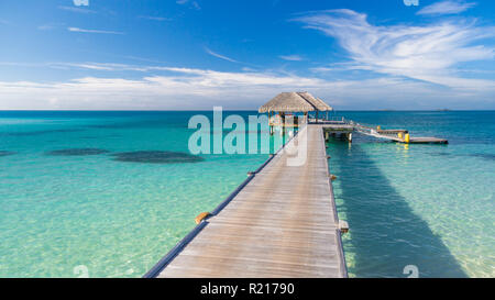 Molo in legno sul bellissimo mare maldiviano con cielo blu. Tranquillo paesaggio di viaggio, mare. Maldive isole Foto Stock