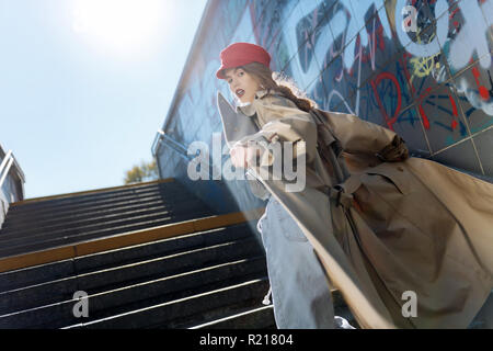 Elegante modello della foto con labbra rosse indossando berretto rosso e beige coat Foto Stock