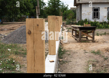 Fondazione in cemento per recinzione. Produzione di calcestruzzo di base per una staccionata di legno. Foto Stock