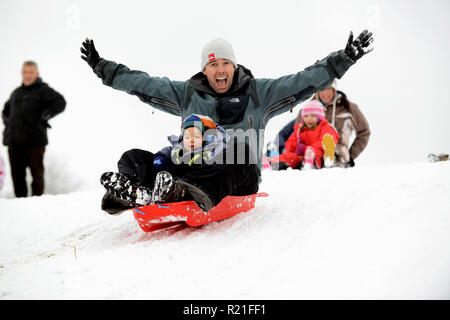 Padre e figlio slittano in Shropshire Winter scena Gran Bretagna Regno Unito Famiglie che slittano su Ironbridge 2017 persone bambini neve Foto Stock