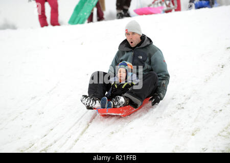 Padre e figlio slittano in Shropshire Winter scena Gran Bretagna Regno Unito Famiglie che slittano su Ironbridge 2017 persone bambini neve Foto Stock