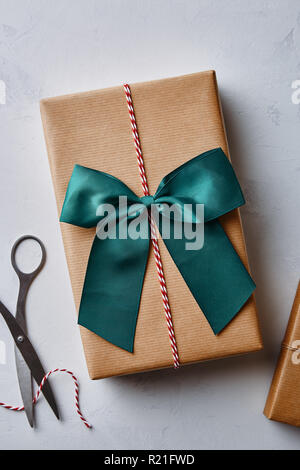 Regalo di natale avvolto in carta marrone con spago, prua e forbici. Vista da sopra Foto Stock