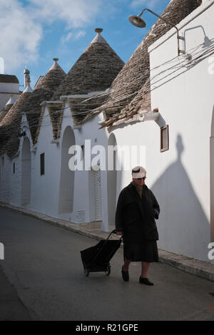 Alberobello,l'Italia,11/15/2018; anziani donna con il suo carrello un autunno mattina sulla strada trulli va shopping . Foto Stock