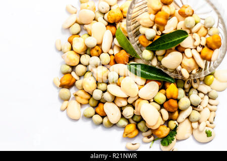Materie organici essiccati misti freschi impulsi o grani misti in una ciotola di vetro isolato su bianco. Foto Stock