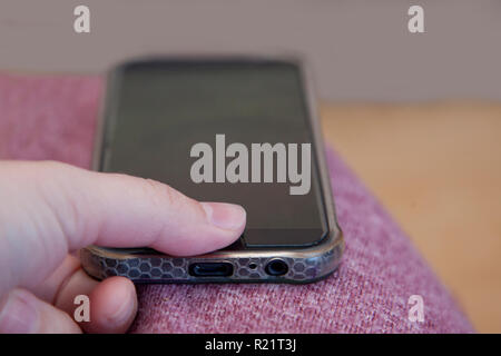 Thumb presses on a mobile phone to unlock the screen with a secure print Foto Stock