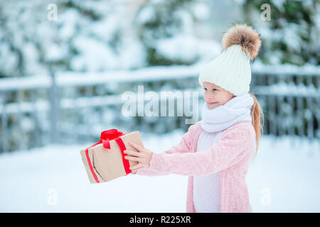 Adorabile ragazza con scatola di Natale regalo in inverno all'aperto su la vigilia di Natale Foto Stock