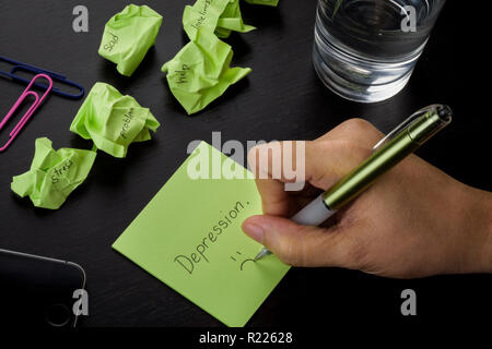 Una scrittura a mano su un verde nota adesiva la parola 'depression." una foto di depressione, tristezza e solitudine. Crumpled green sticky note sparse. Foto Stock