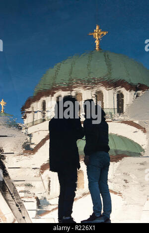 Sfocata la riflessione di San Sava tempio ortodosso e alcune persone si avvicina, sul bagnato pavimentazione della città di Belgrado, Serbia Foto Stock