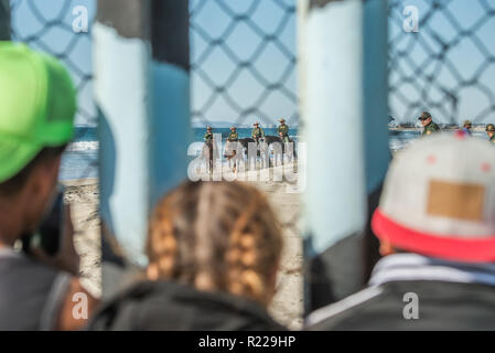 Tijuana, Messico. Xiv Nov, 2018. I richiedenti asilo provenienti da America centrale, aka il "migranti Caravan' guardare sul confine come agenti Patrol a cavallo di arrivare sulla scena a noi/Messico frontiera. Credito: Vito Di Stefano/ZUMA filo/Alamy Live News Foto Stock