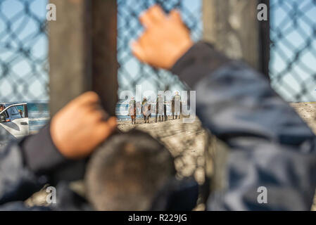 Tijuana, Messico. Xiv Nov, 2018. Richiedente asilo dall America Centrale, aka il "migranti Caravan' guardare attraverso la recinzione di confine come confine agenti Patrol a cavallo arrivano all'US/Messico frontiera. Credito: Vito Di Stefano/ZUMA filo/Alamy Live News Foto Stock