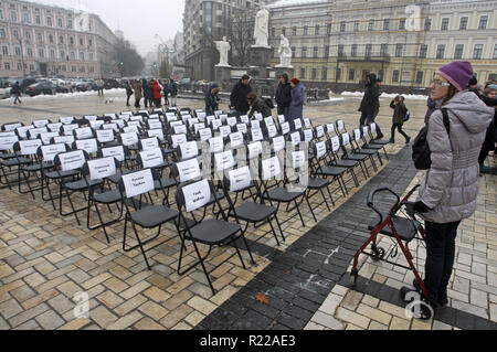 Kiev, Ucraina. Xv Nov, 2018. Una donna guarda sulle sedie vuote con fogli allegati con nomi di ucraini di prigionieri politici in Russia, durante le prestazioni simbolico chiamato ''free sedie sulla San Michele Square a Kiev in Ucraina, il 15 novembre 2018. Il rally volti a sostenere il regista Oleg Sentsov e ucraino altri prigionieri politici in Russia, in Crimea e la zona di conflitto dell'est di ucraino. Una sedia vuota simboleggia un autore che non può essere presente su un particolare evento in un risultato di reclusione, detenzione, sparizione, un pericolo per la vita o di omicidio. (Immagine di credito Foto Stock