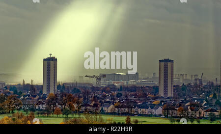 Glasgow, Scotland, Regno Unito, 16 novembre 2018. Regno Unito Meteo Meteo un avviso di tempesta in anticipo con una giornata noiosa come raggi crepuscolari noto come raggi di Dio appaiono su knightswood campo da golf, il sud di Glasgow, pietre miliari locali come le torri Scotstoun, Queen Elizabeth University Hospital e il Titan Crane, l'ultimo residuo della cantieristica locale sul fiume Clyde. Credito: gerard ferry/Alamy Live News Foto Stock