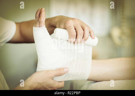 Fisioterapista bendaggio mettendo su feriti i piedi del paziente Foto Stock