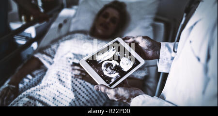 Medico maschio guardando sonography relazione su una tavoletta digitale Foto Stock