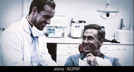 Dentista discutendo su tavoletta digitale con paziente di sesso maschile Foto Stock
