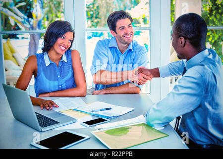 Coppia felice stringono le mani con agente immobiliare Foto Stock