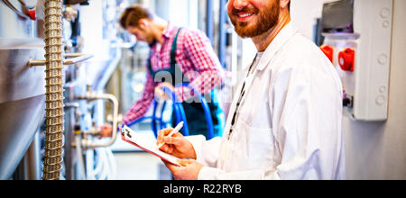 Lavoratori di manutenzione esaminando brewery macchina Foto Stock