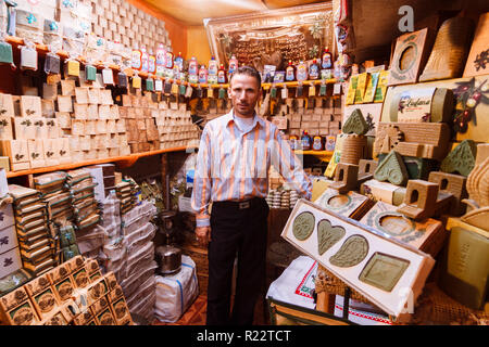 Aleppo, Governatorato di Aleppo, Siria : un venditore sorge presso il suo negozio di al-Madina Souq visualizzando il famoso sapone Aleppo prodotti. Foto Stock