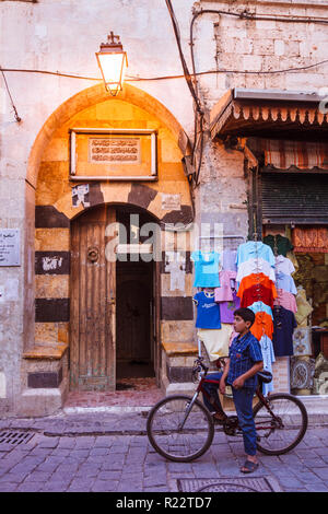 Aleppo, Governatorato di Aleppo, Siria : un bambino su una bicicletta sorge da una moschea in uno stretto vicolo del centro storico. Foto Stock