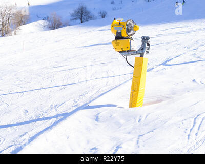Giallo cannoni da neve sulle piste da sci. L innevamento macchina utilizzata in un caldo inverno a mantein il manto di neve Foto Stock