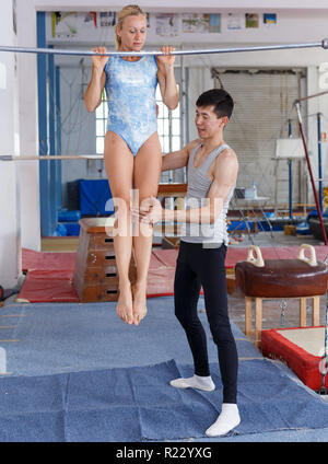 Montare l uomo e la donna facendo esercizi acrobatici in palestra che fissano ciascun altro Foto Stock