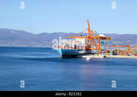 Nave container per il trasporto di merci con container a terra in porto la nave porta sull orizzonte / Cargo il trasporto via mare di merci e il processo di scarico. Foto Stock