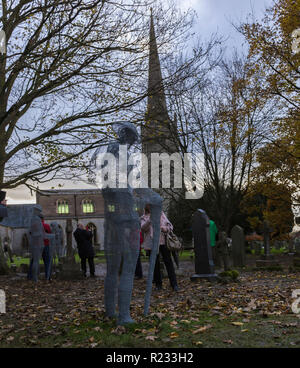 "Ghostlike' sculture (dall artista Jackie Lantelli) di soldati morti nella guerra mondiale uno accanto alle loro tombe nel cimitero di Slimbridge Foto Stock