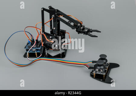 Piccolo braccio di robot con joystick su sfondo grigio Foto Stock
