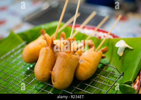 Fresca asiatici fritti speziati calamari fritti salsiccia stick sul mercato locale a Bangkok. Cucina tailandese tradizionale fatta di ingredienti freschi. Foto Stock