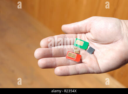 Close-up di un maschio di mano, tenendo mazzetto dei colorati carte SIM Foto Stock