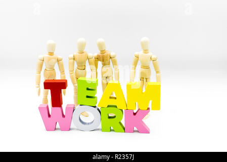 Figure in legno che si presentano come uomini di affari dietro la parola il lavoro di squadra, isolato su bianco. Team, unità e concetto di collaborazione Foto Stock