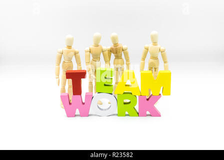 Figure in legno che si presentano come uomini di affari dietro la parola il lavoro di squadra, isolato su bianco. Team, unità e concetto di collaborazione Foto Stock