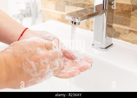 Persona di risciacquo mani insaponata sotto inox rap con acqua in esecuzione Foto Stock