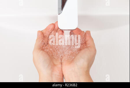 Donna bagnare le mani sotto inox tocca da vicino come personale concetto di igiene Foto Stock