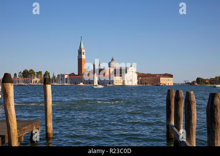 San Giorgio Isola Maggiore e basilica a Venezia, pali di legno e pier nella calda luce del tramonto, Italia Foto Stock